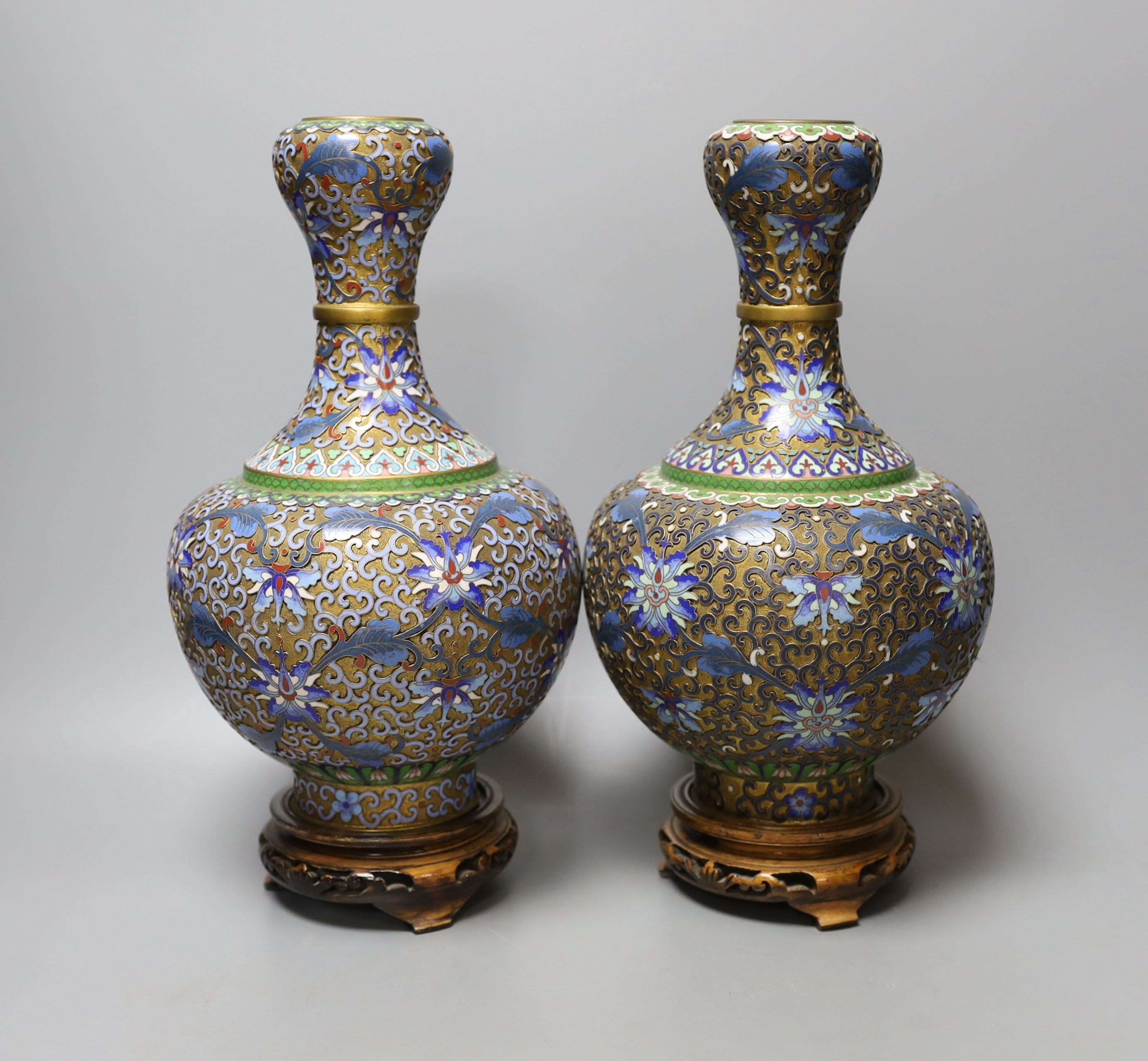 A pair of Chinese cloisonné enamel vases, on carved wood plinths, 30cm